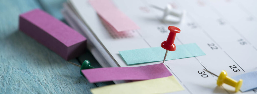 Post-its and a thumb tack on a desk calendar