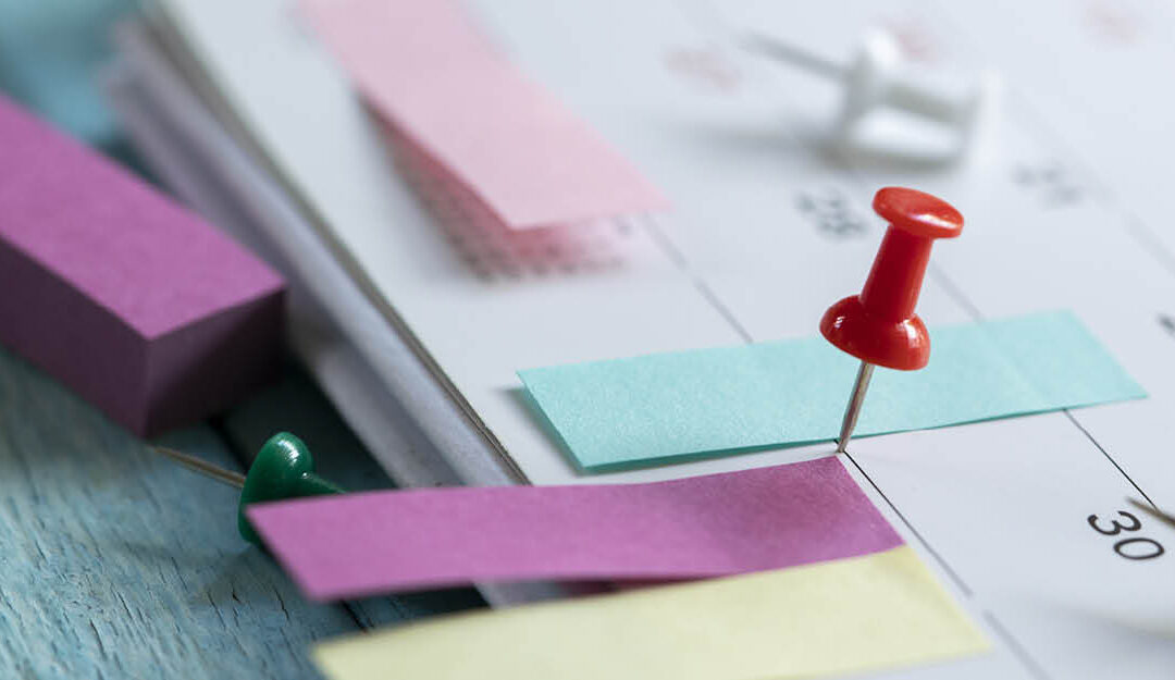 Post-its and a thumb tack on a desk calendar